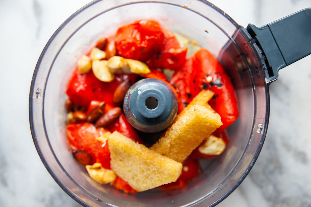 Place peepers, tomatoes, bread, garlic, vinegar, salt, paprika, and almonds in blender and pulse briefly. 