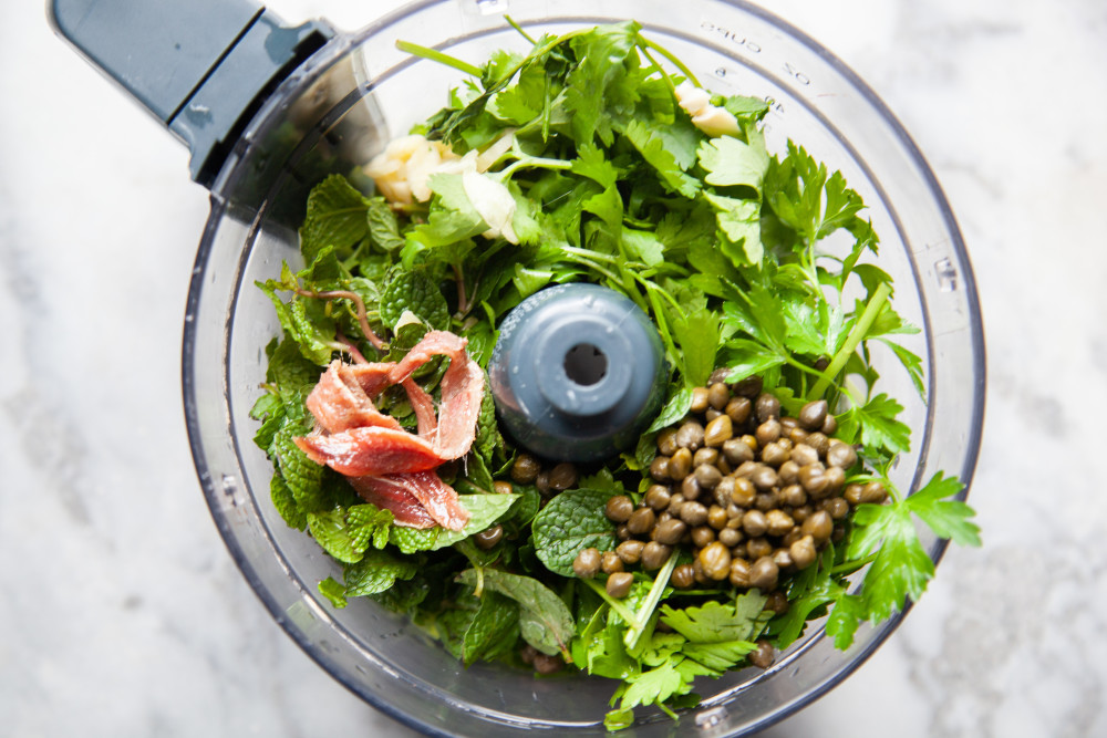 Place herbs, garlic, anchovies, and capers in food processor or blender and pulse a couple of times. 