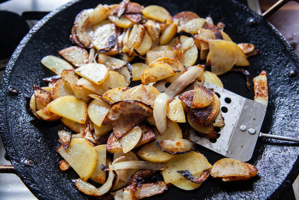 Heat half of the olive oil in a large skillet or griddle. Add onions and potatoes and saute over medium high heat until potatoes are cooked through and crispy. Season to taste with salt and pepper.