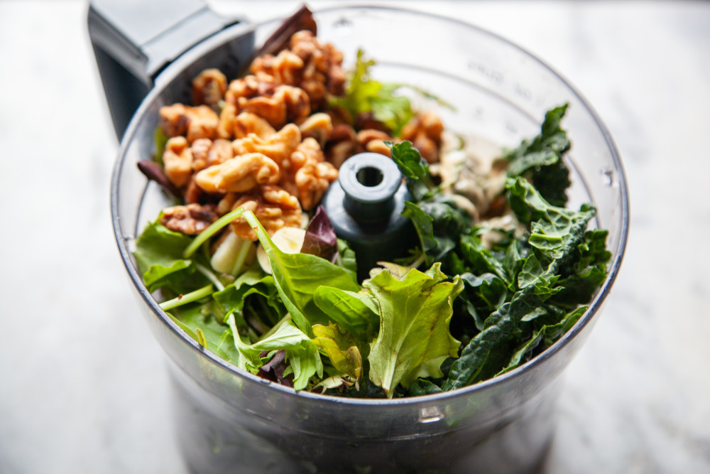 Place greens, garlic, tahini, and walnuts in food processor and pulse a few times. 