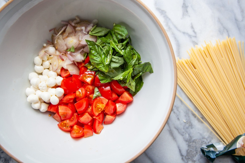 While spaghetti is cooking, toss chopped tomatoes, shallots, basil and mozzarella with olive oil in a large bowl.