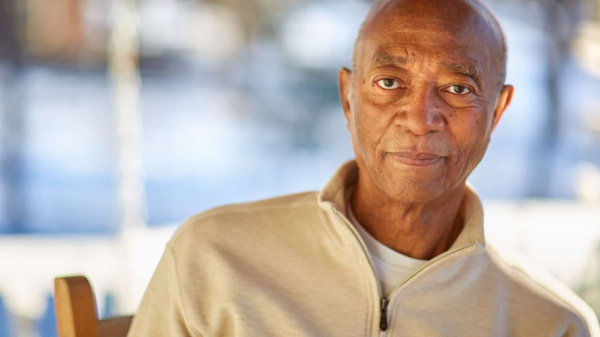 Three photos in one image. Photo one is of two adults looking at prostate cancer medicines, one adult is one the phone. Photo two is of an adult looking at the camera. Photo three if of two adults looking at a prostate cancer study brochure. 