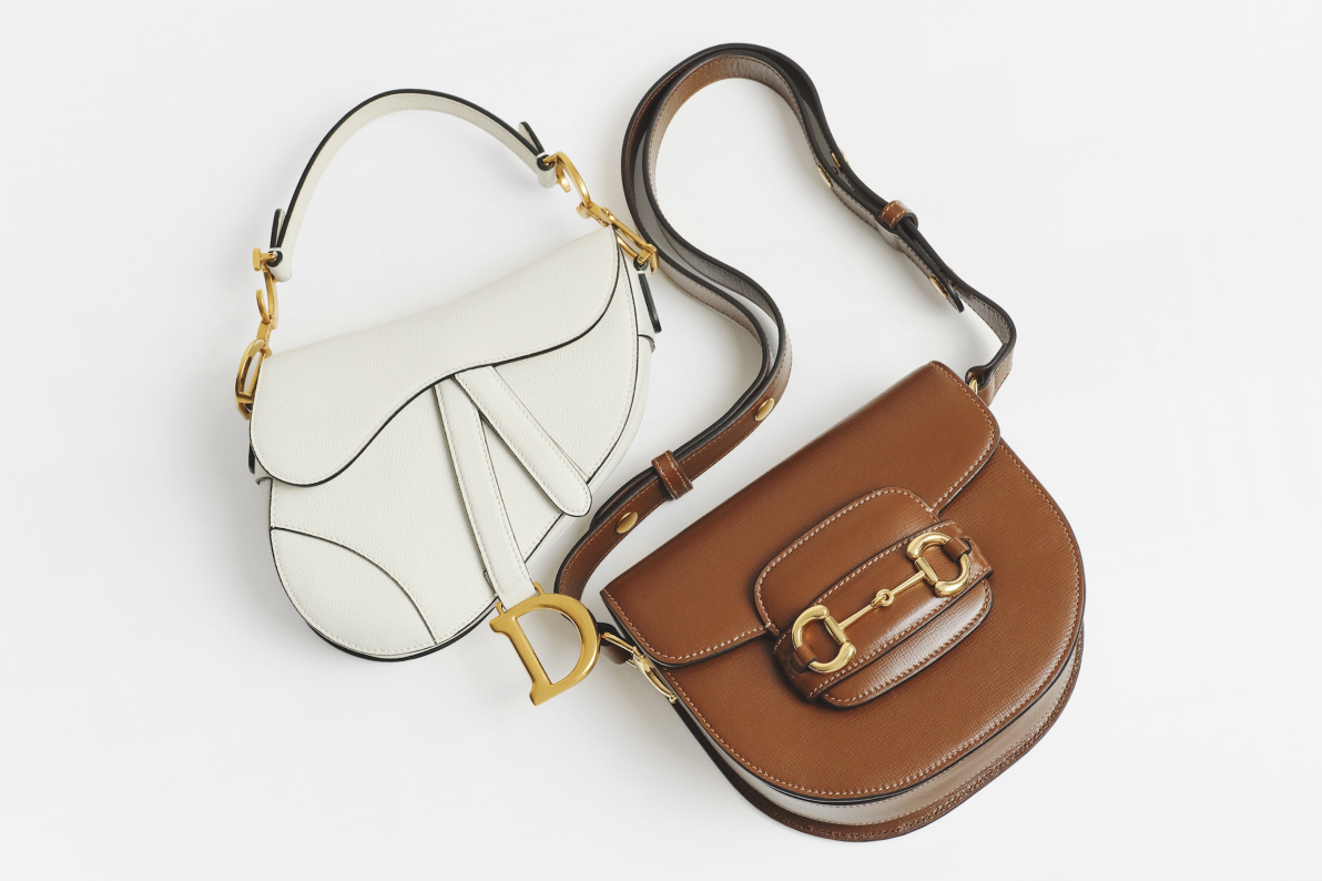 one white Christian Dior Saddle bag lying next to one brown Gucci Azalea Calfskin Mini Horsebit 1955 Rounded Shoulder Bag 