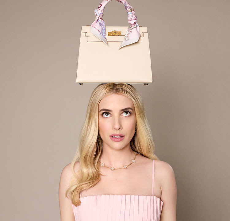 Emma Roberts in a pink dress with a white Hermes Kelly and an Hermes twilly wrapped around the handle sitting on her head