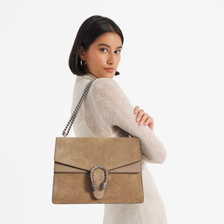 a woman in a cream long sleeve dress holding a GUCCI Suede Medium Dionysus Shoulder Bag Taupe