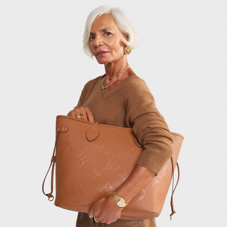 influencer Grece Ghanem wearing a tan v-neck sweater and a tan leather midi skirt and holding a tan color Louis Vuitton leather monogram Empriente Neverfull tote bag