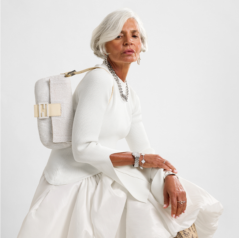 a woman in a white long dress holding a white beaded Fendi Baguette