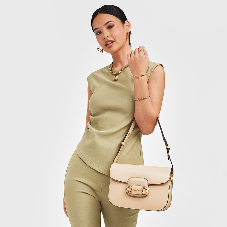 a woman in a green two piece pant and top holding a GUCCI Azalea Calfskin Horsebit 1955 Shoulder Bag in Mystic White