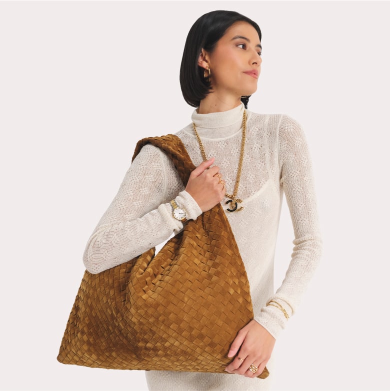 a woman in a cream long sleeve dress holding a BOTTEGA VENETA Suede Intrecciato Large Hop Acorn