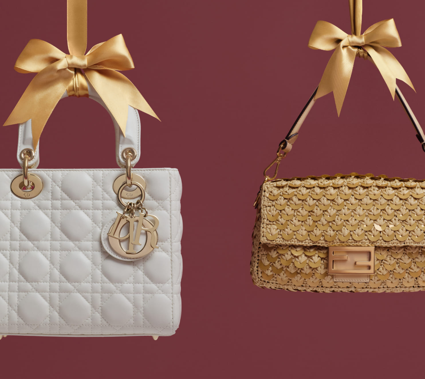 one cream color Christian Dior Lady Dior bag hanging from a gold satin bow and one crochet raffia Fendi Baguette bag with gold sequins hanging from a gold satin bow against a burgundy color background