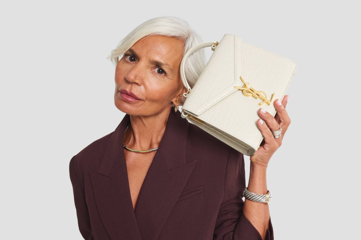 influencer Grece Ghanem wearing a burgundy suit and holding a white Saint Laurent Cassandra top handle bag with a YSL yellow gold logo hardware clasp