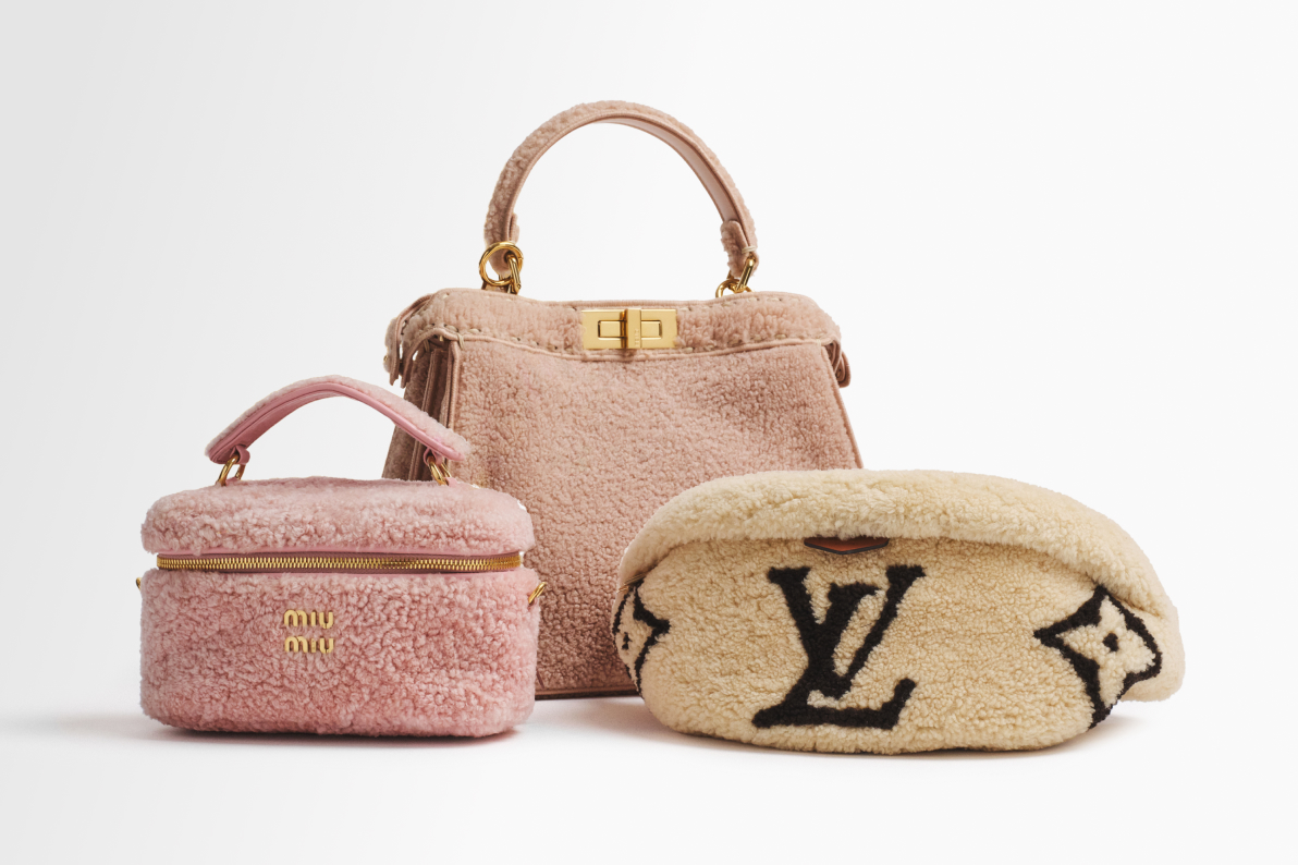 a wood Chanel snowboard with Gucci snow goggles hanging off of it sitting along with a pink shearling Miu Miu vanity case bag, a shearling light pink Fendi Peekaboo top handle bag, and a beige shearling monogram Louis Vuitton Bumbag