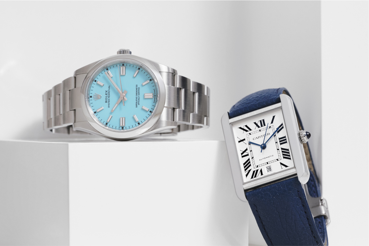 one ROLEX Stainless Steel Oyster Perpetual Watch Turquoise lying next to one Cartier Stainless Steel Calfskin Tank Solo Automatic Watch Blue