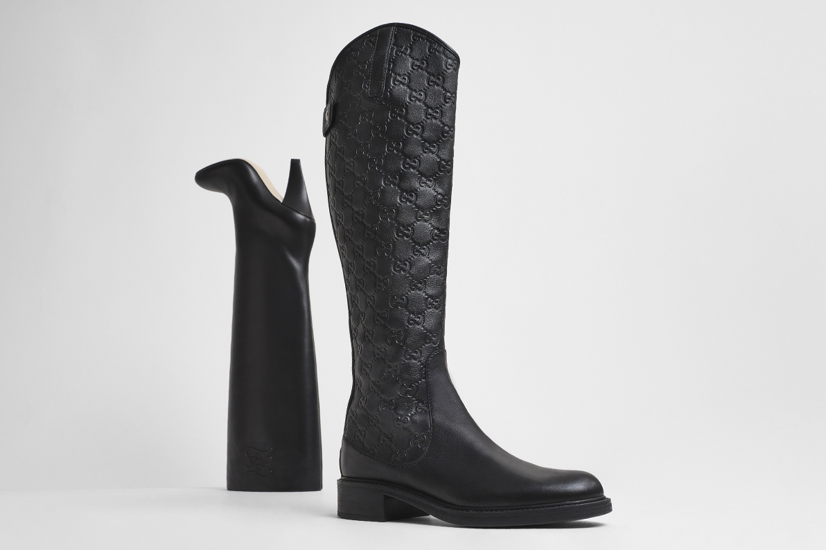 one black GUCCI Guccissima Calfskin Miro Soft Knee High Riding Boot standing in front of one black FENDI Vitello Karligraphy Embossed Knee High Boots standing upside down