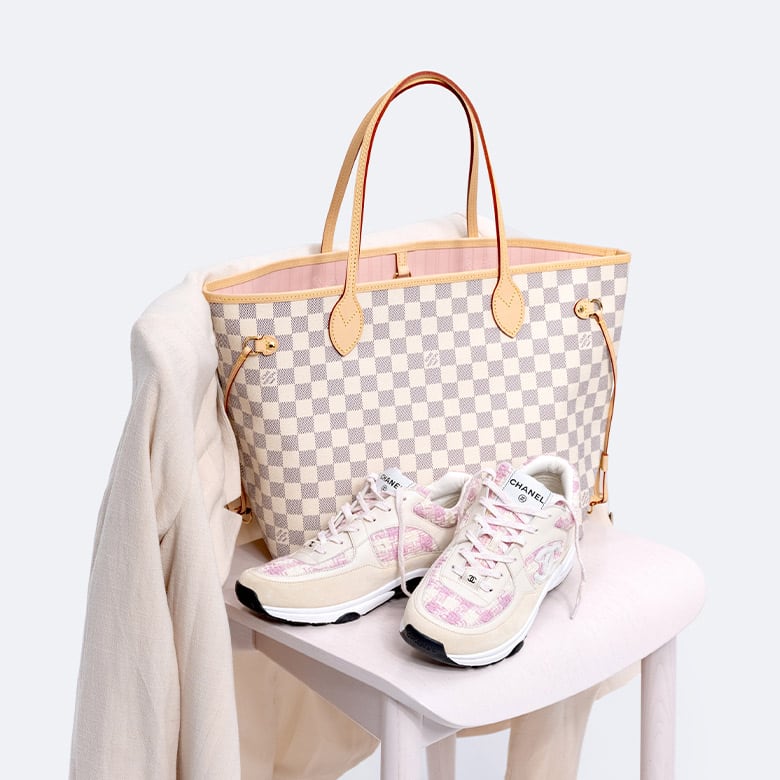 One Louis Vuitton Damier Azur Neverfull MM tote bag and a pair of Chanel pink tweed sneakers sitting on a chair