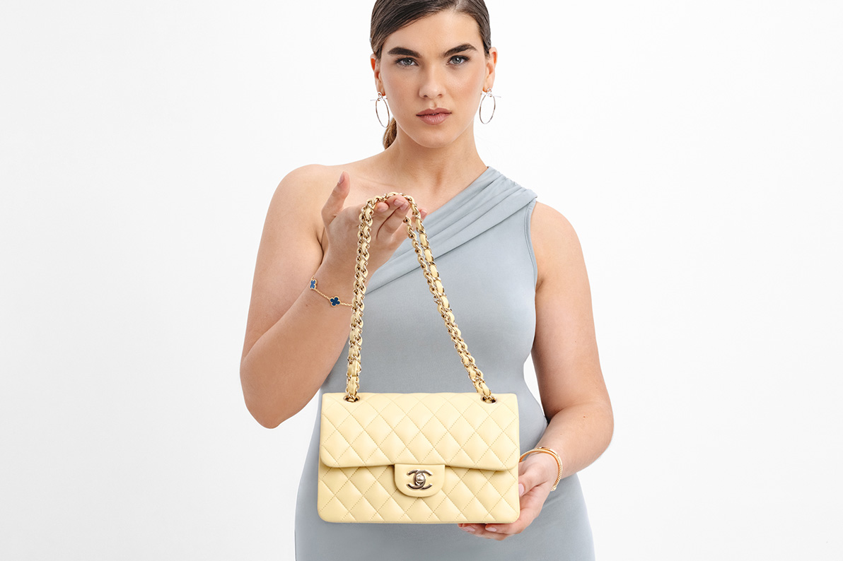 a woman in a grey dress holding a yellow Chanel Double Flap