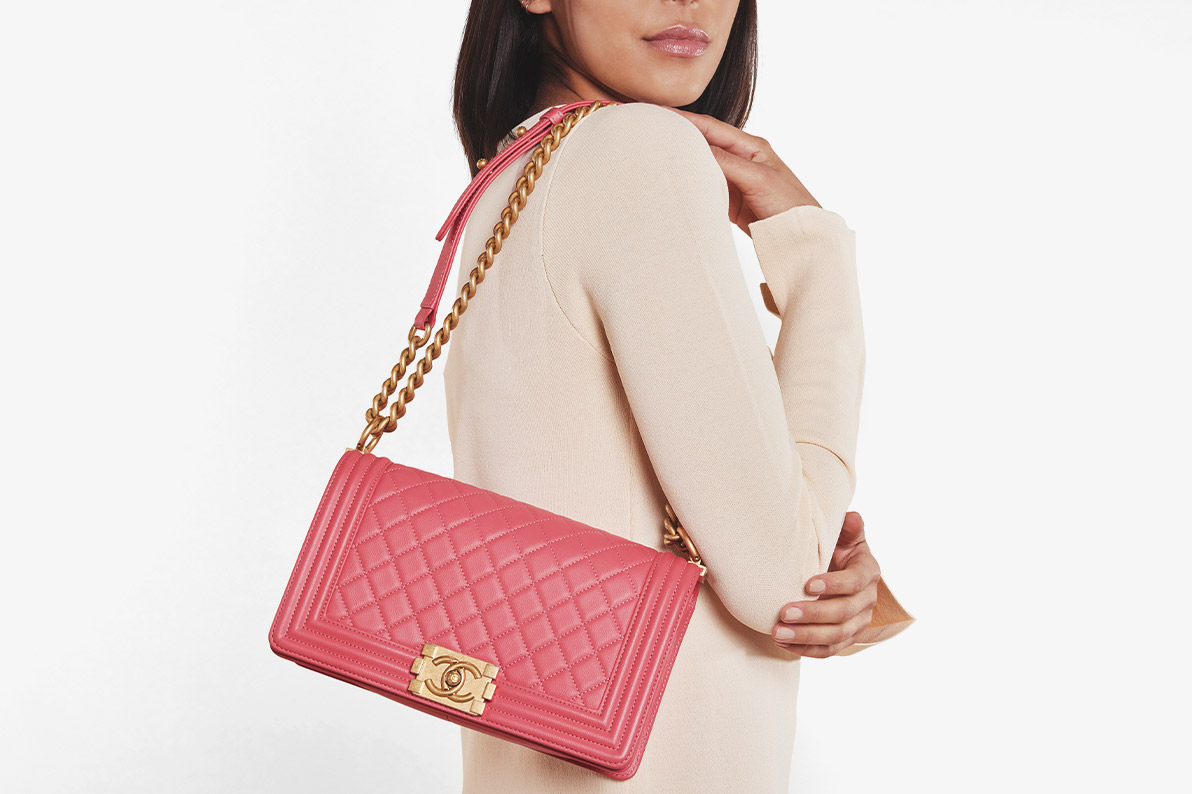 a woman in a cream long sleeve dress holding a pink CHANEL Lambskin Quilted Boy Flap