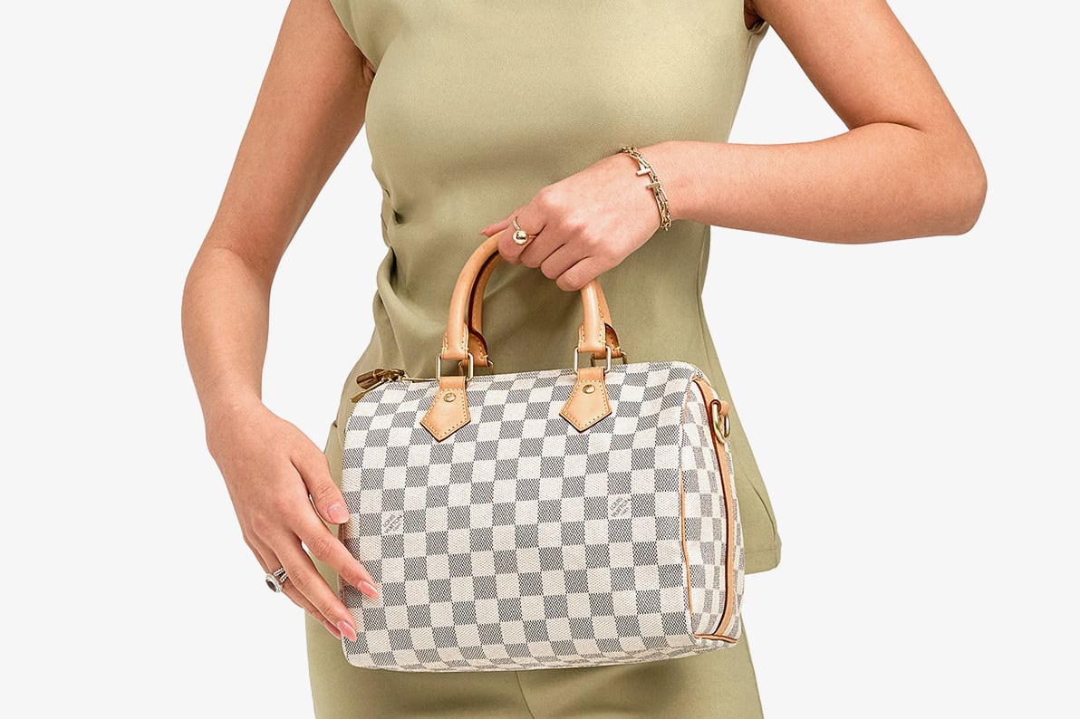 a woman in a green top and matching green pants holding a Louis Vuitton Damier Azure Speedy 