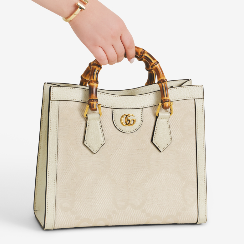 a woman's hand holding a white Gucci Diana bag