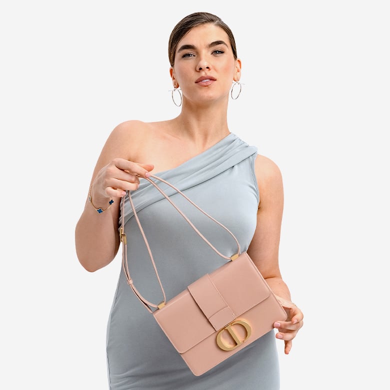 a woman in an off shoulder grey dress holding a CHRISTIAN DIOR Shiny Crinkled Lambskin 30 Montaigne Flap Bag