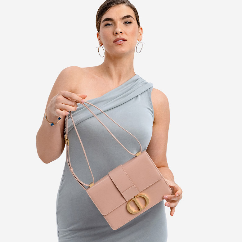 a woman in an off shoulder grey dress holding a CHRISTIAN DIOR Shiny Crinkled Lambskin 30 Montaigne Flap Bag