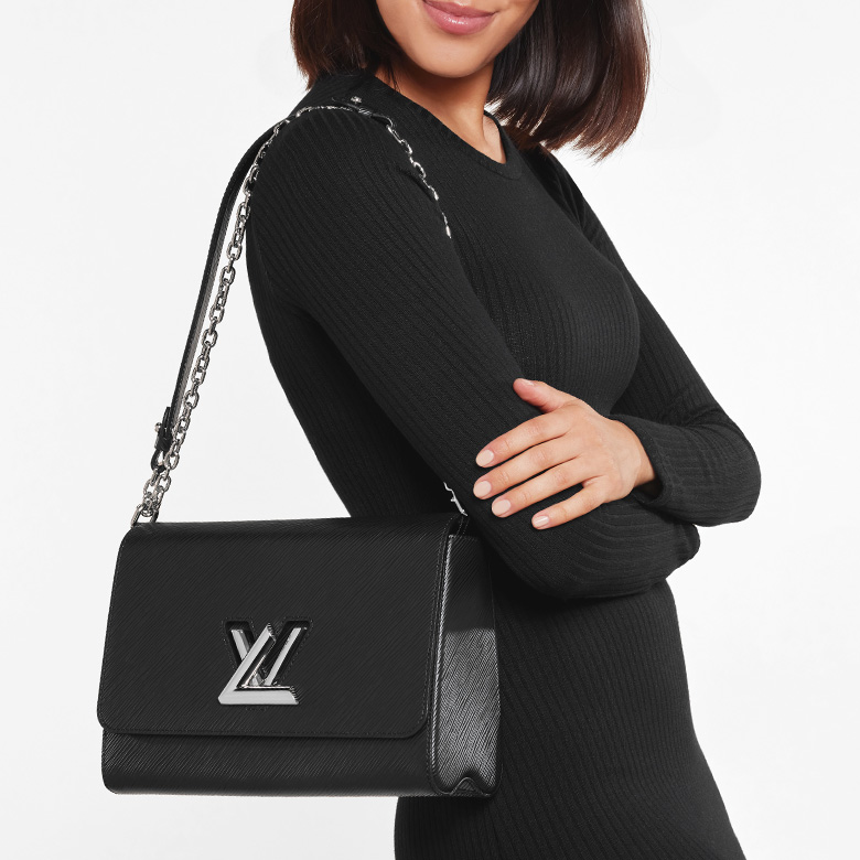 a woman in a black long sleeve dress wearing a black Louis Vuitton Epi LockMe bag