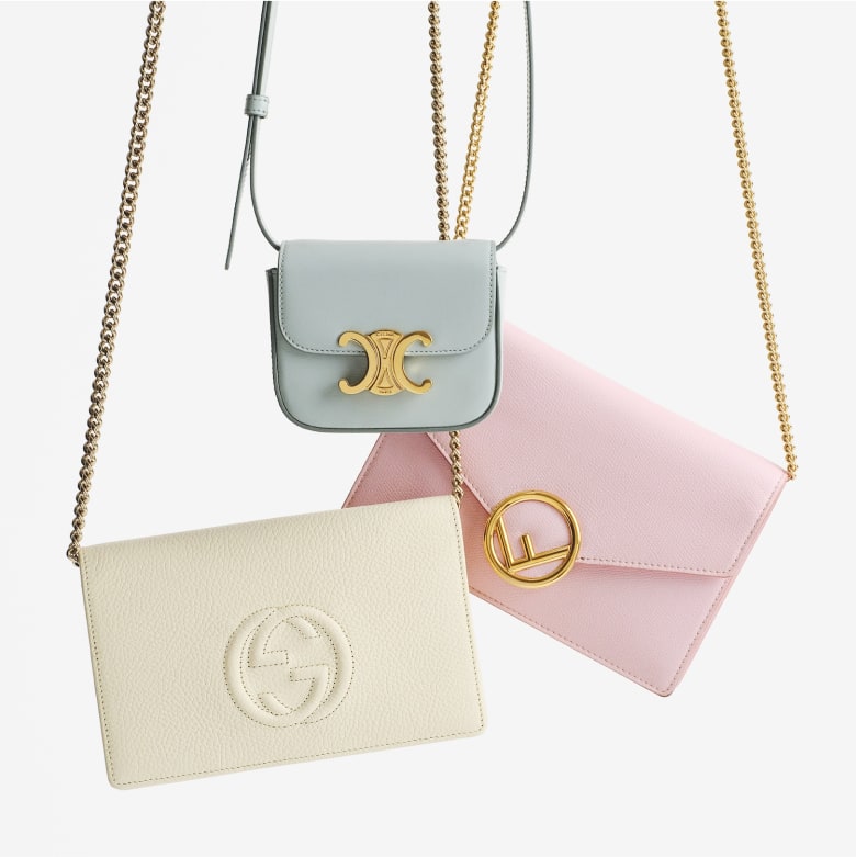 one white GUCCI Pebbled Calfskin Soho Wallet On Chain hanging next to one CELINE Shiny Calfskin Mini Claude Soft Blue and one FENDI Vitello Cruise F is Fendi Medium Envelope Wallet on Chain Peonia