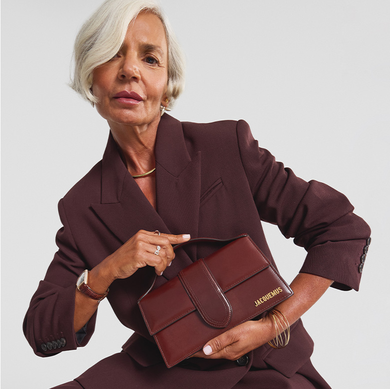 influencer Grece Ghanem wearing a burgundy color matching suit blazer and pants and holding a dark brown Smooth Calfskin Le Grand Bambino bag 