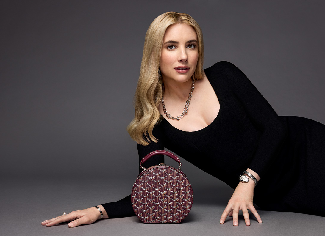 Emma Roberts wearing a black long sleeve dress with a burgundy GOYARD Goyardine Alto Hatbox