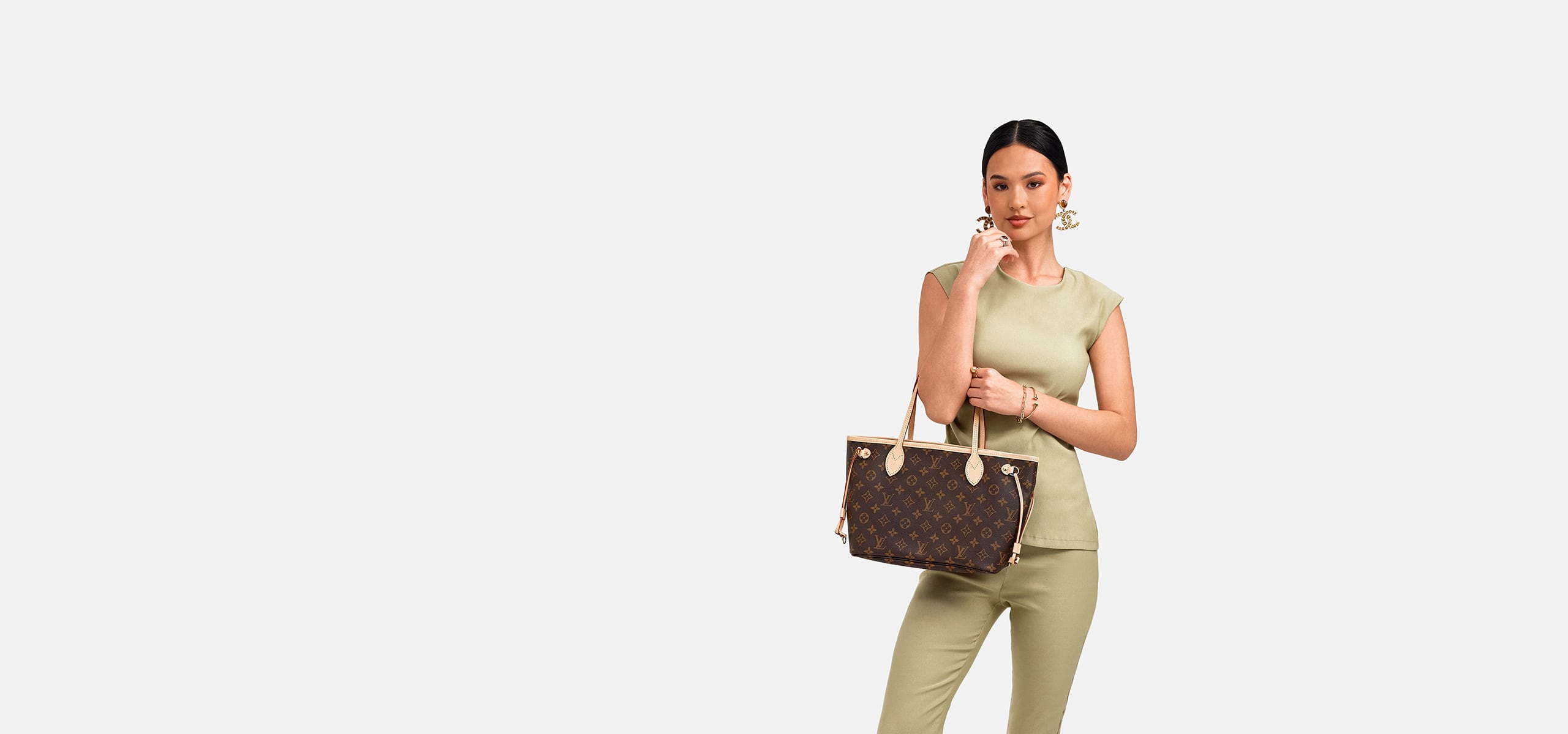 a woman in a green top and matching pants holding a Louis Vuitton Monogram Neverfull PM