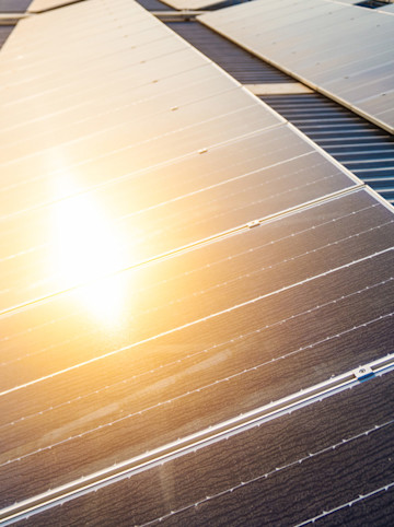 Nahaufnahme von Solarmodulen auf einem Hausdach mit starker Sonnenreflexion.