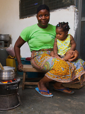 Kochende Frau mit Kind in Ghana
