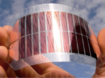 Eine Hand biegt eine handgroße, flexible Folie aus organischen Solarzellen.