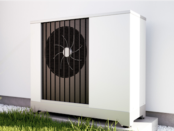 Mit Solarstrom betriebene Wärmepumpe in weiß mit großem Ventilator stehend vor weißer Hauswand mit Gras im Vordergrund.