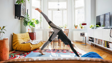 Frau macht Yoga im Wohnzimmer