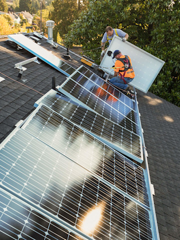 Handwerker installieren Solaranlage auf Hausdach