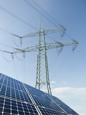 Teil eines Solardachs mit Hochspannungsmast und blauem Himmel im Hintergrund.