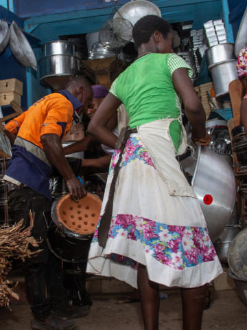 Kochende Frau mit Kind in Ghana