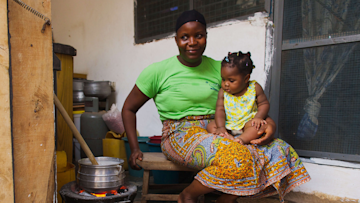 Kochende Frau mit Kind in Ghana