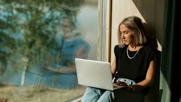 Frau am Laptop vor dem Fenster