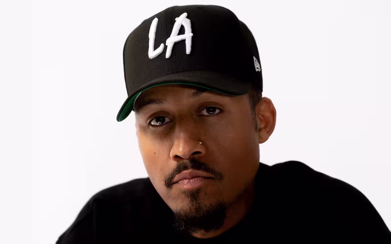 Gavin Mathieu wearing a black cap with "LA" embroidered in white, dressed in a black shirt, set against a plain white background.