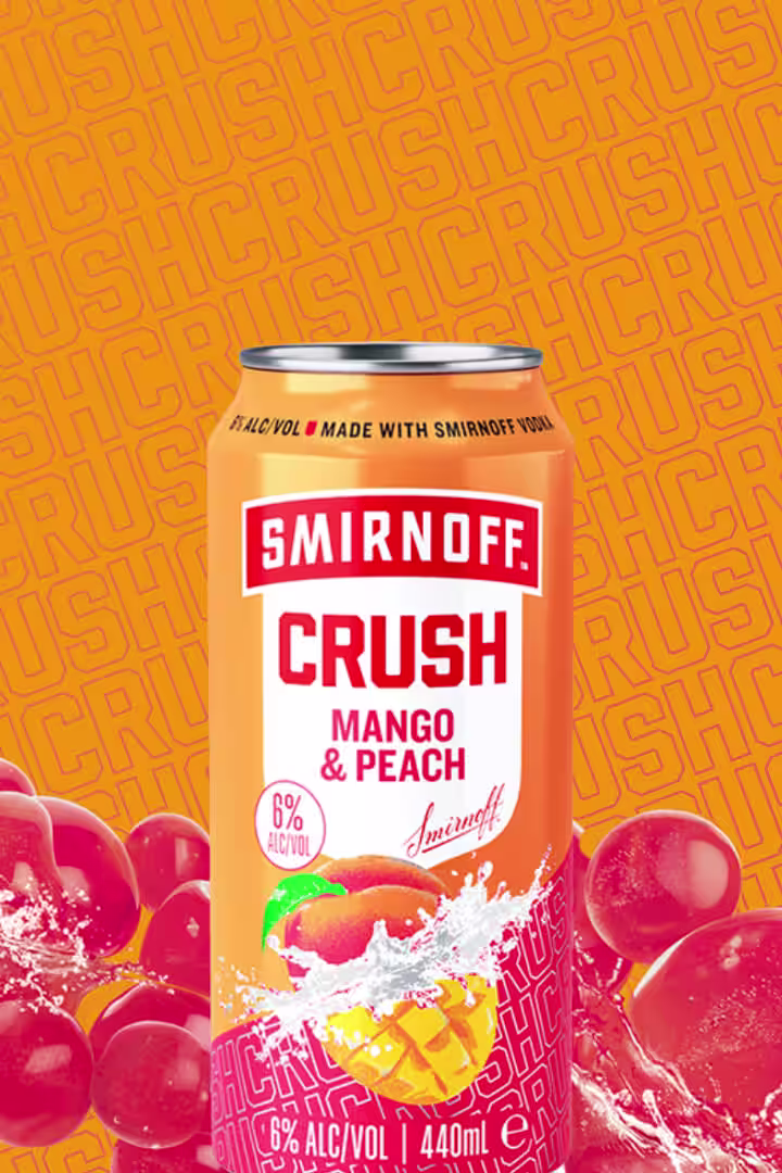 A vibrant can of Smirnoff Crush Mango & Peach, featuring fruity mango and peach flavors. Contains 6% alcohol by volume, 440ml size, set against an orange background with splashes of fruit imagery.