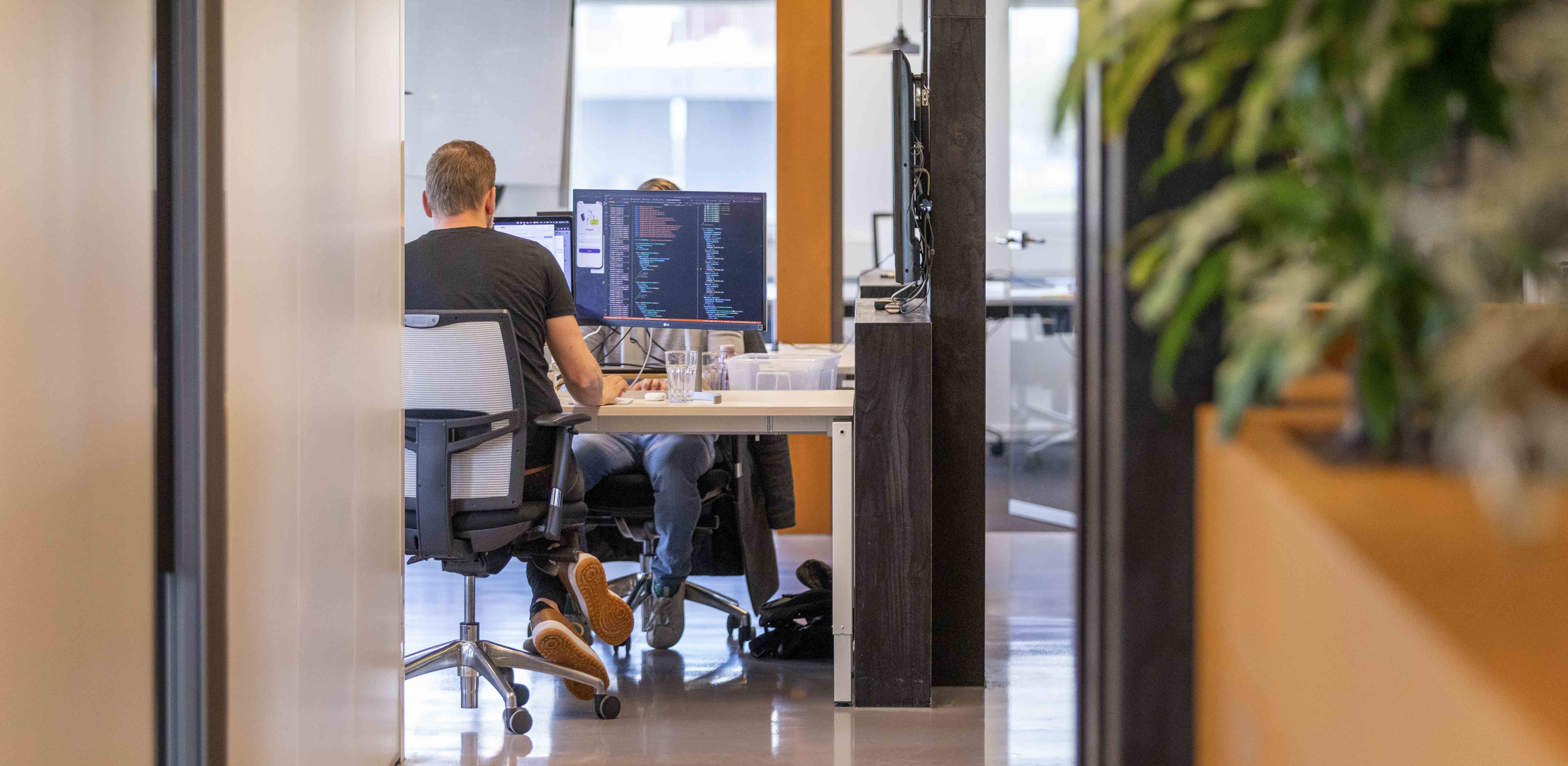 Je ziet in de verte een developer werken aan een werkeiland. 