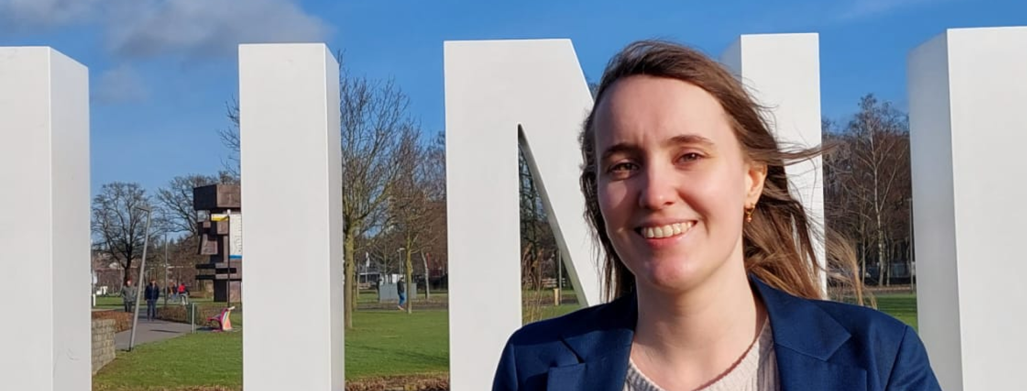 Laura voor de grote letters van Universiteit Twente