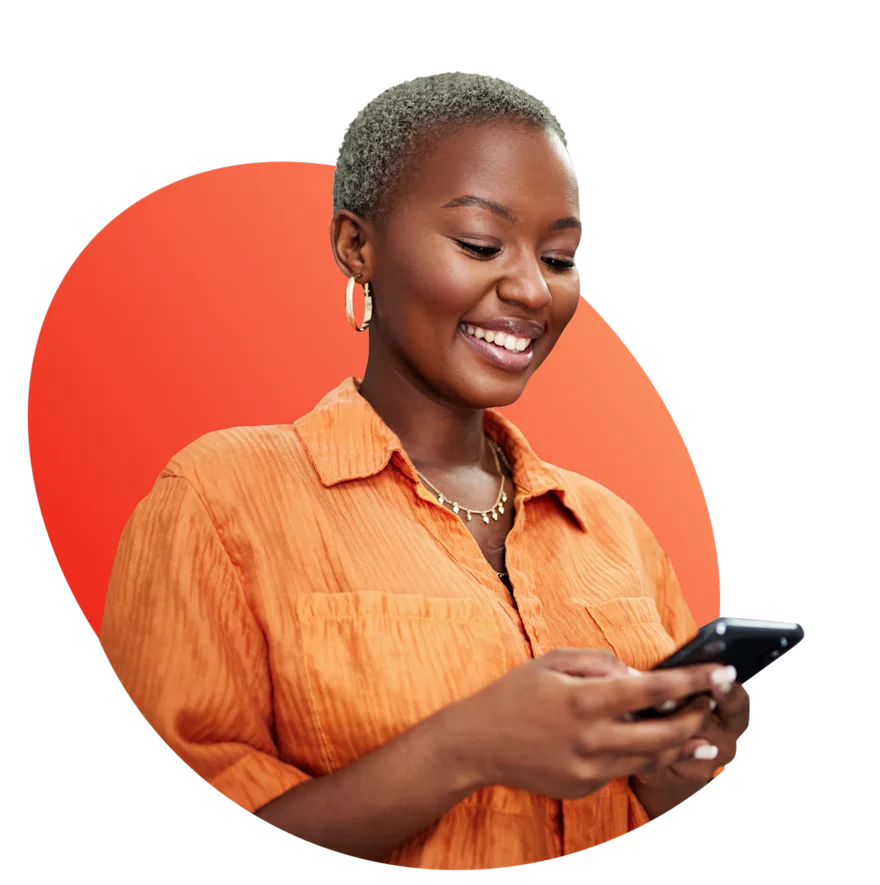 woman in orange shirt smiling down at phone in hands