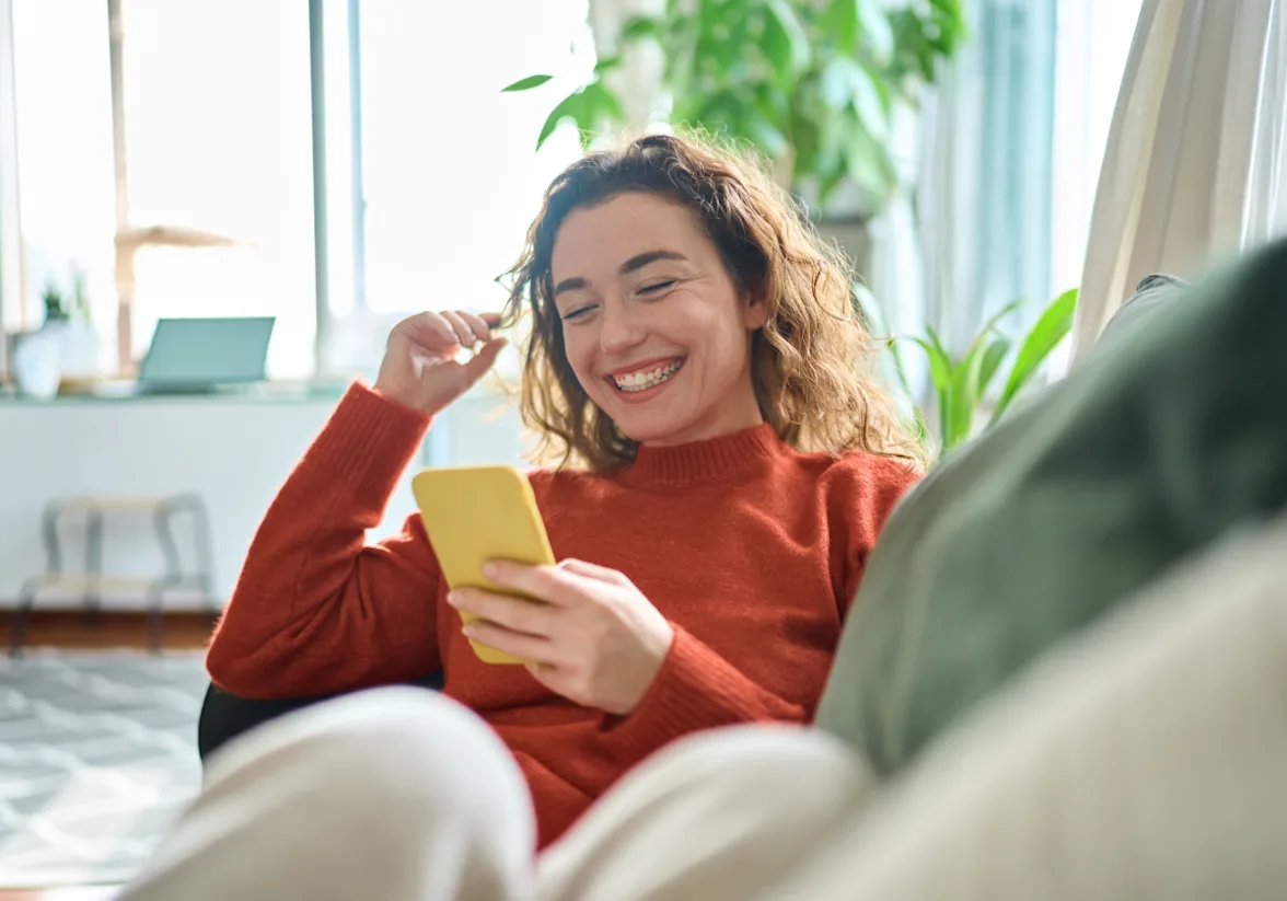 Photo of woman on couch looking at mobile phone
