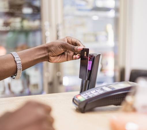Picture of a hand holding and touching a card on a payment machine.
