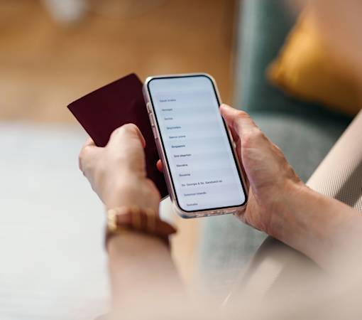 Image shows a person holding a passport and a mobile