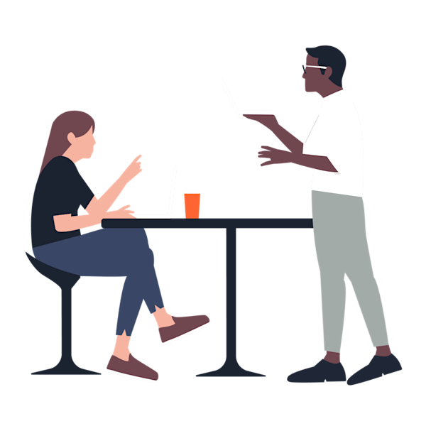 In a corporate environment, a woman sits while engaging in conversation with a man who is standing. Both are looking at their notebooks and discussing a business project.