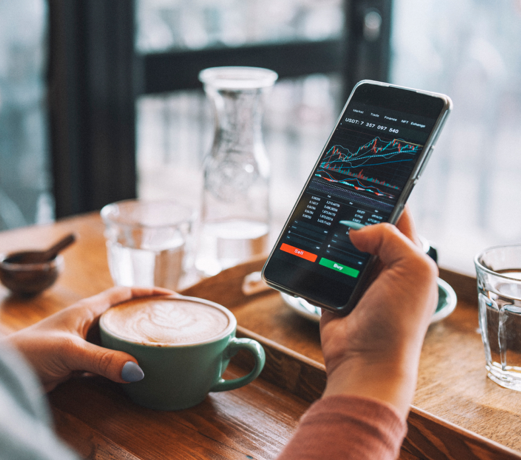 A picture of a hand holding a phone that displays investments.